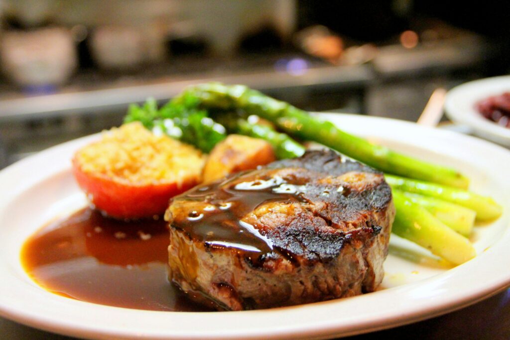 Steak in brown sauce, tomato with parmesan cheese and asparagus